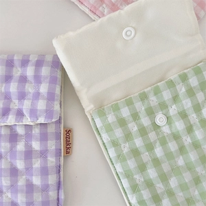 Close-up of quilted cotton sanitary pouch showing metallic snap button and grid texture