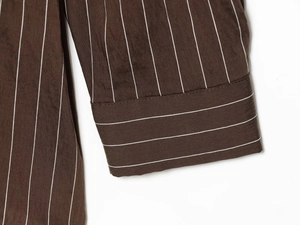 Detail of dark brown striped shirt cuff showing fine stitching and textile texture