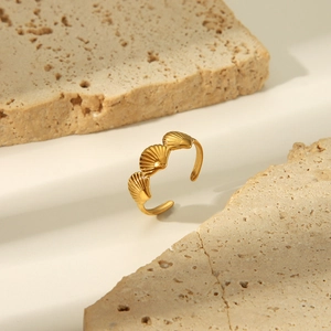 Detailansicht eines goldenen Muschelrings auf beigem Stein mit weichem natürlichem Licht