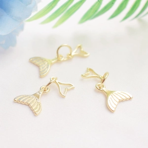 Trois pendentifs en forme de queue de poisson dorée pour bijoux DIY sur fond floral