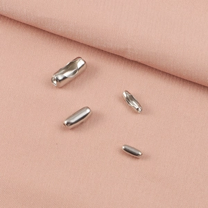 Polished stainless steel bead chain connectors in various sizes on pink fabric background