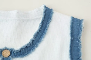 Détail de maille blanche avec bordure bleue vieillie et bouton doré embossé