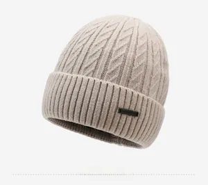 Close-up of beige cable knit beanie showing thick texture and black woven label detail