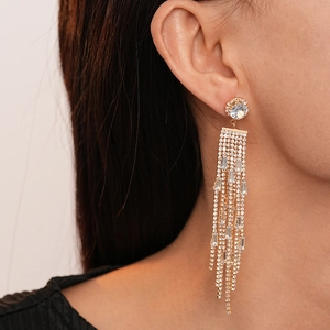 Close-up of elegant long gold tassel earrings with sparkling rhinestones on a female model