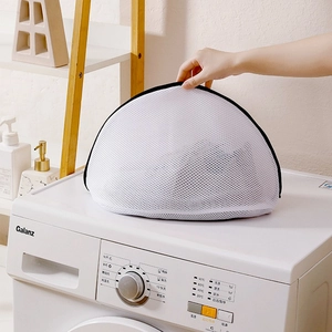 Close-up of white mesh shoe laundry bag with black zipper on top of a washing machine