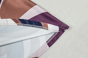 Close-up of precise overlock stitching on the geometric print hem of a mini dress