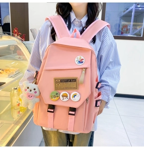 Pink nylon school backpack detail featuring a cute plush bear charm and cartoon badges