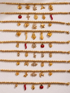 Detail von goldenen Bambusketten-Armbändern mit bunten Zirkonia-Anhängern und Kreuzen