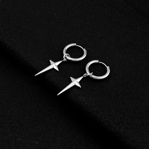 Macro view of polished stainless steel cross star earring on matte black surface