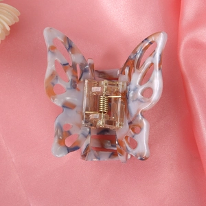 Macro shot of butterfly hair clip with marble texture on pink silk background
