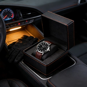 Luxury quartz watch with brown leather strap displayed in a carbon fiber box inside a car