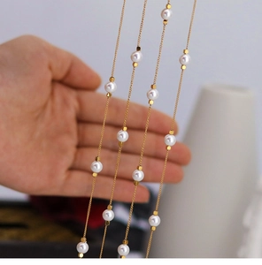Detailed macro view of gold chain with five round pearls and small metal beads