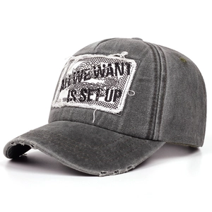 Detail of vintage washed gray baseball cap with distressed brim and letter embroidery