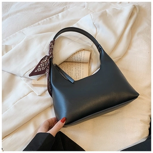 Detail of black hobo shoulder bag with geometric print silk scarf on a book background