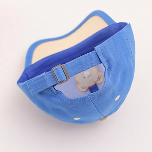 Detail of adjustable metal strap buckle and teddy bear patch on blue kids baseball cap
