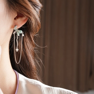 Close-up of elegant long silver tassel earrings with green floral and pearl accents