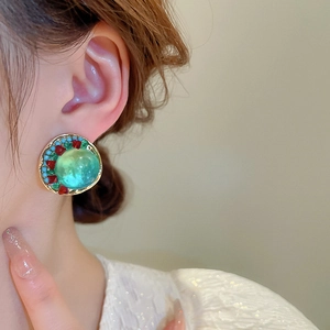 Vue latérale macro de boucles d'oreilles vintage en or avec verre vert et diamants