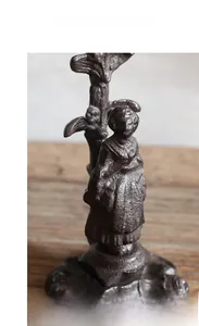 Detail of vintage cast iron candle holder featuring a girl figure with rustic texture
