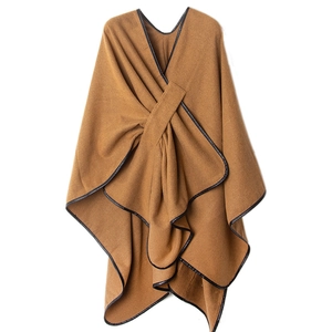 Close-up of brown knit poncho featuring black faux leather trim and cross knot detail