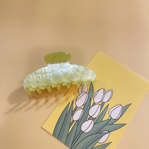 Detail view of a pale yellow translucent hair claw clip with a subtle grid texture