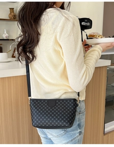 Detail of grey crossbody bag with geometric circle pattern worn on a knitted sweater