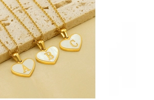 Detailed view of heart-shaped gold necklace pendant with white shell and letter A B C