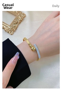 Detail view of a gold-plated open bangle featuring polished beads and sparkling crystal row