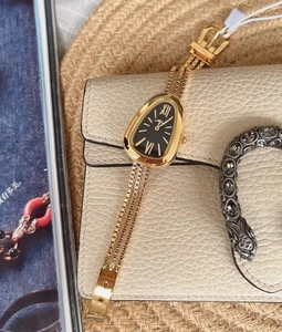Detailed view of luxury gold snake head watch with textured serpent scale bracelet