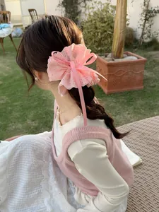 Pink lace scrunchie with delicate ribbon bow shown on a ponytail in a sunny outdoor setting