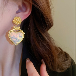 Gros plan de boucles d'oreilles cœur vintage avec détail rose sur un mannequin