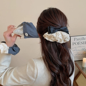 Détail d'une pince à cheveux avec nœud en dentelle brodée sur de longs cheveux ondulés