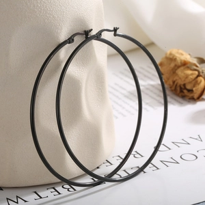 Fashionable oversized black matte stainless steel hoop earrings for women on a beige vase