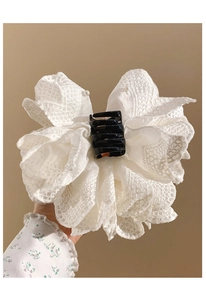 Detail of white lace bow hair claw clip with delicate pearl accents and floral patterns