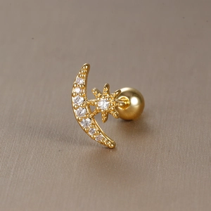 Macro detail of gold star and crescent moon earring with micro-set cubic zirconia crystals