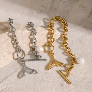 Detail of gold and silver fishtail bracelets with baroque pearls and OT clasps