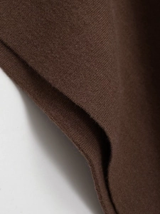 Macro detail of dark brown knit fabric texture showing premium soft wool fibers