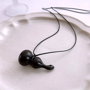 Gros plan d'un collier pendentif calebasse en bois noir sur une assiette blanche