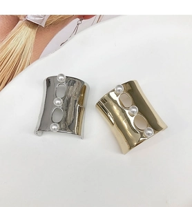 Close-up of gold and silver U-shaped hair clips with three elegant white pearls