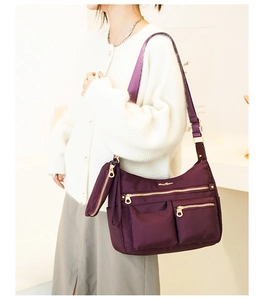 Detail view of purple waterproof nylon shoulder bag with adjustable strap and small pouch