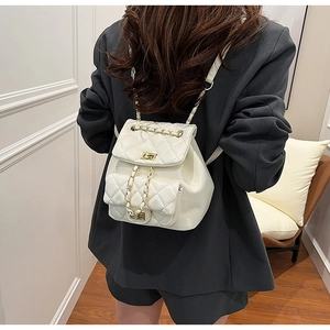 Detail of cream quilted backpack featuring gold metal clasps and leather chain straps