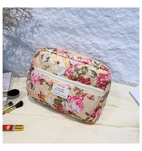 Floral quilted cosmetic bag with front zipper pocket on a wooden background