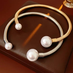 Detail view of gold and silver metallic choker necklaces with pearl ends on leather box