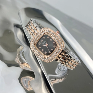 Detailed close-up of a women's square green watch with a diamond-set bezel and metal strap