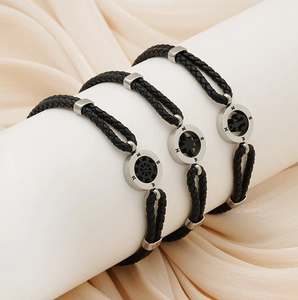 Detailed view of three-piece black woven leather bracelets with nautical steel charms