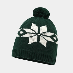 Detail of dark green knit hat featuring white snowflake patterns and a fluffy pom-pom
