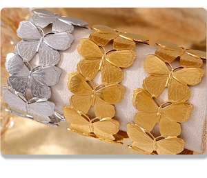 Detail of butterfly bangles in gold and silver finish on soft velvet display stands