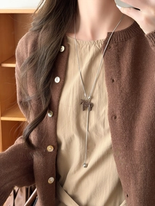 Close-up of minimalist stainless steel necklace with brown pony pendant on a model