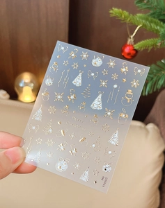 Detailed macro view of 3D gold and silver Christmas nail stickers with snowflakes and bows