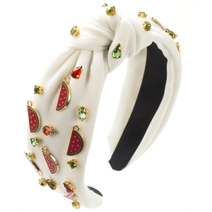 Détail d'un serre-tête en tissu blanc avec charms pastèque en émail et strass verts