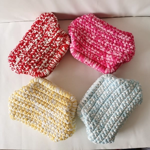 Macro view of four colorful handmade crochet pouch bags with thick yarn textures